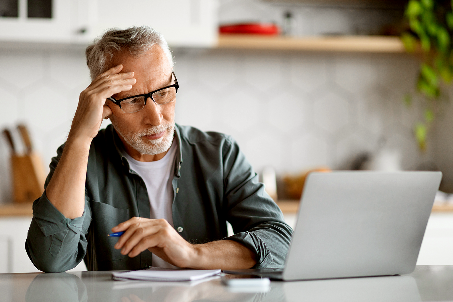 Man looking stressed while reviewing documents on a laptop