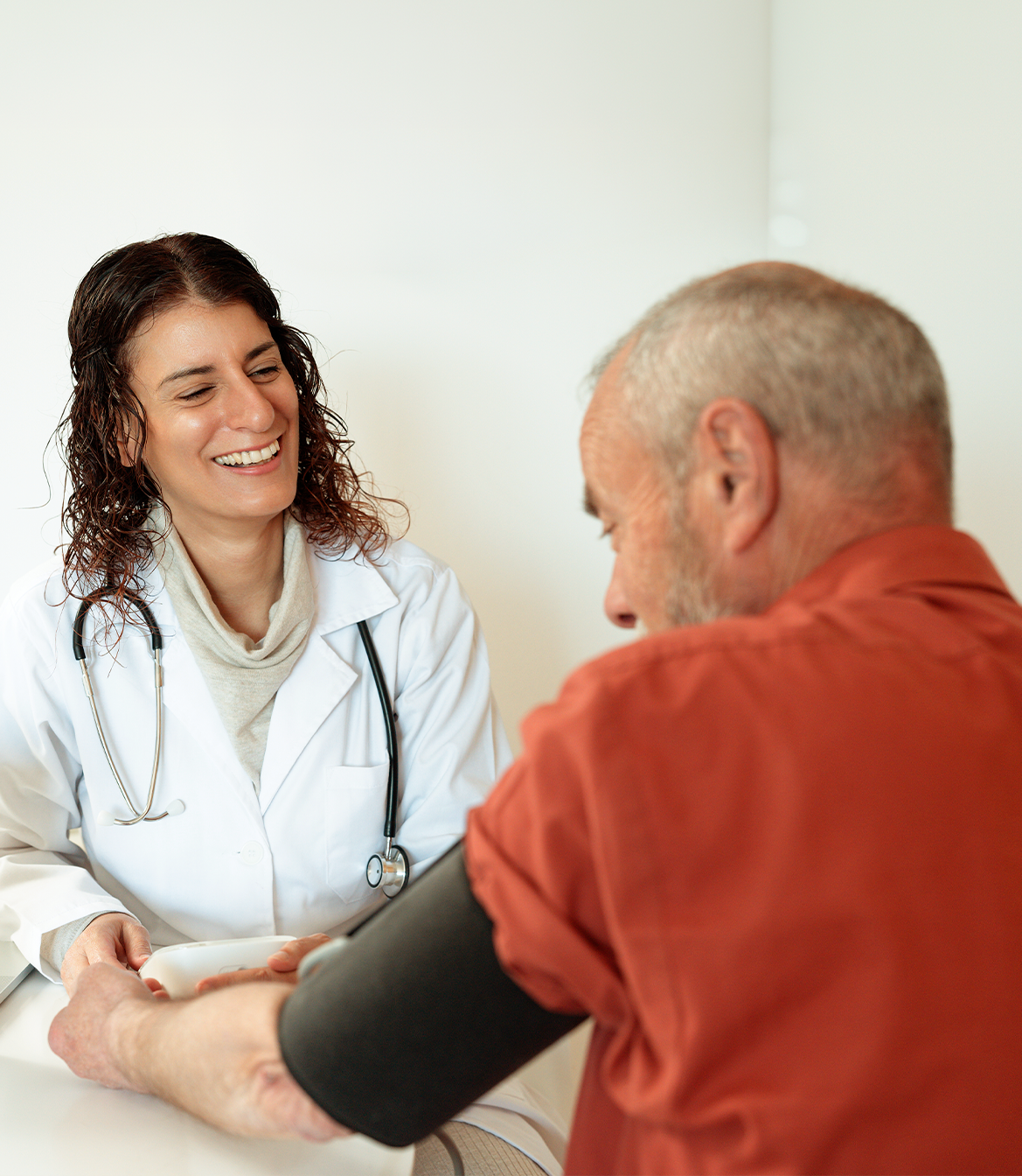 A doctor checking an older patient's blood pressure during an appointment