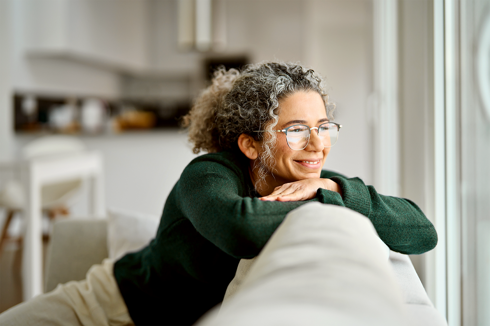 A woman resting on her sofa at home, looking out of the window