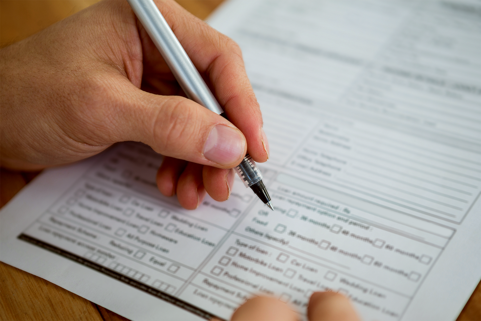 A person filling out a disability benefits application form by hand
